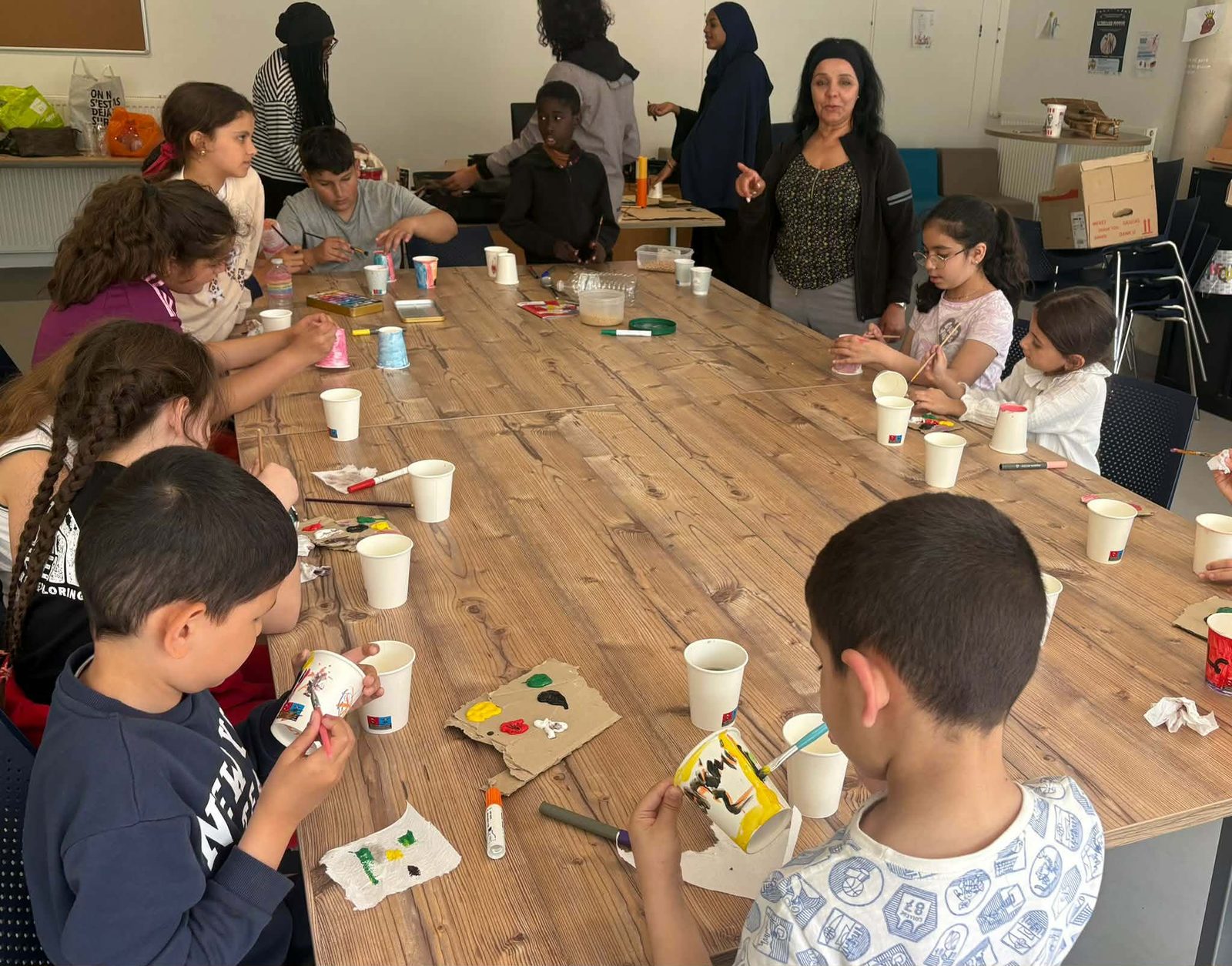 Enfants peignent et décorent des gobelets pendant un atelier de réemploi créatif