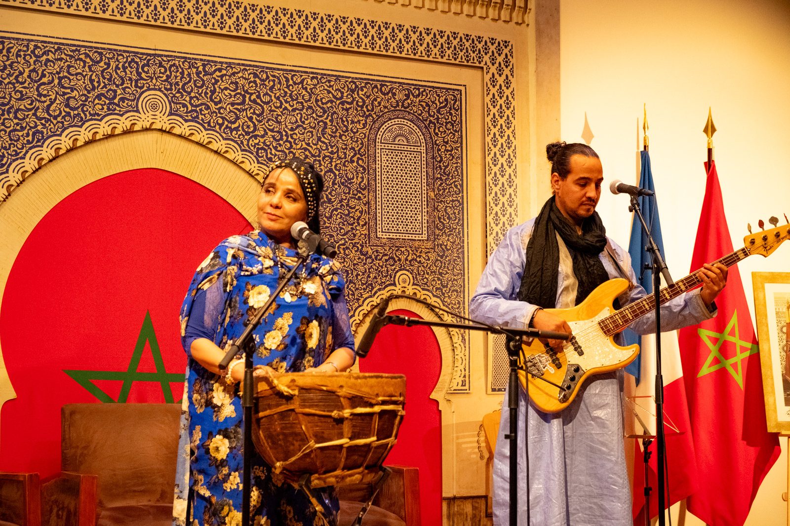 Duo percussion et basse en tenues traditionnelles devant un décor marocain