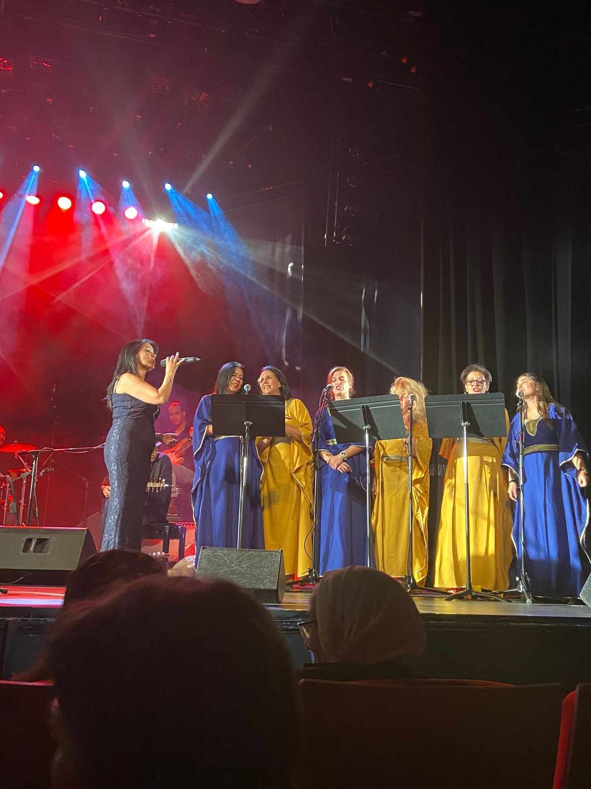 La chorale de femmes en caftans bleus et or chante sur une grande scène